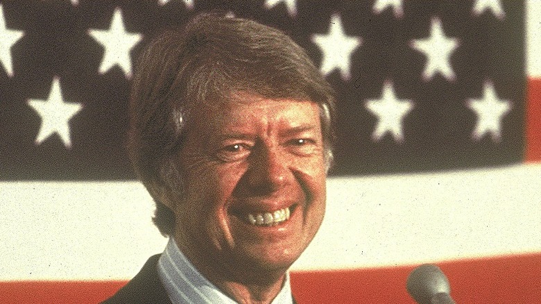 Young Jimmy Carter grinning in front of USA flag