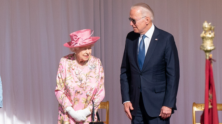 Queen Elizabeth II standing next to President Joe Biden onstage