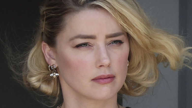 Amber Heard looking serious gold earrings blonde bob