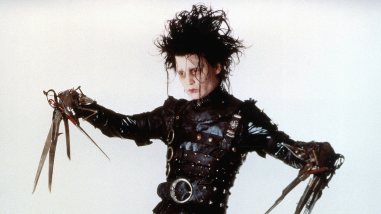 Johnny Depp wearing a black leather suit with belts and using scissor blades for hands