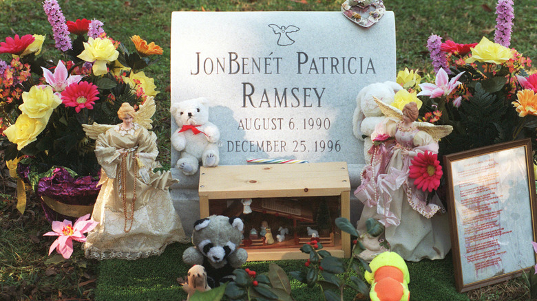 Jonbenet Ramsey's gravestone with flowers and stuffed animals adorning it