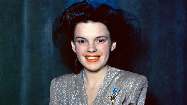 Judy Garland poses in a blue hat and red lipstick