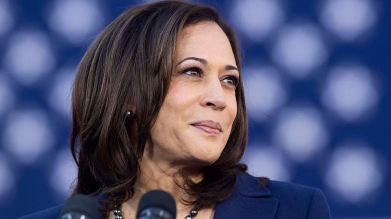 Kamala Harris smiling on stage in front of microphone