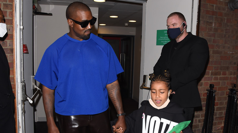 Kanye West holding North West's hand