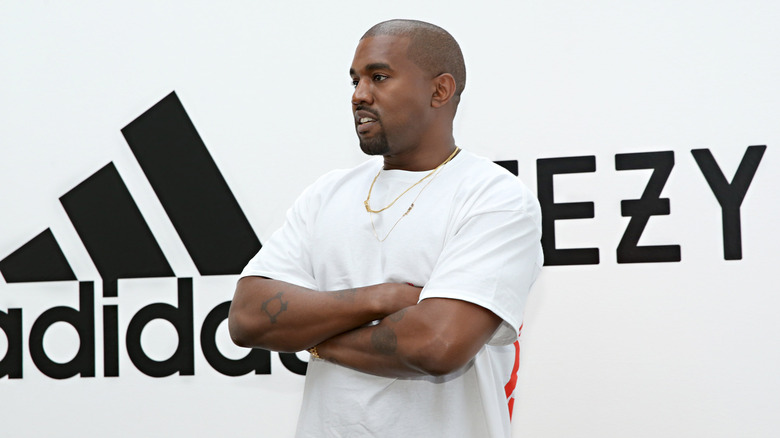 Kanye West standing near Adidas and YEEZY logos