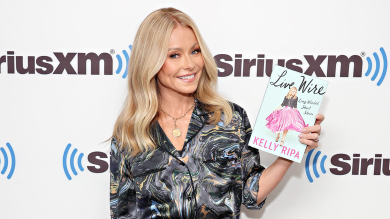 Kelly Ripa holding up her new book 