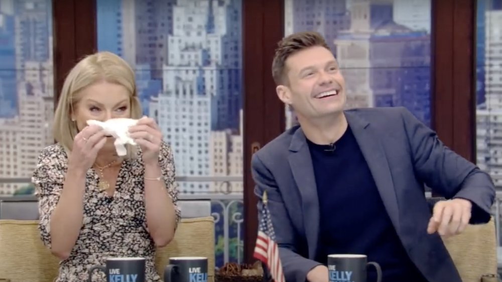 Kelly Ripa with tissues in hand, next to Ryan Seacrest