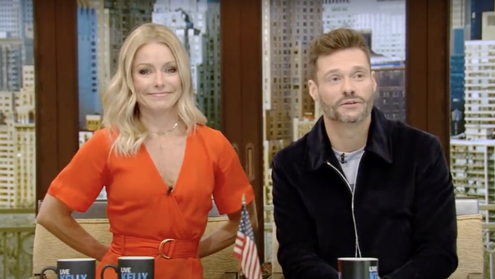 Kelly Ripa smiling in a red dress next to Ryan Seacrest