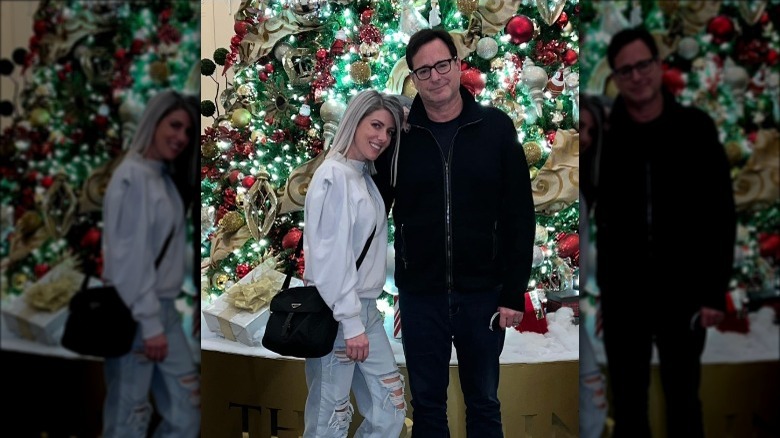 Kelly Rizzo and Bob Saget in front of Christmas tree