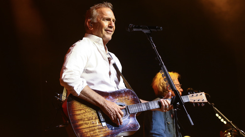 Kevin Costner sings and plays guitar on stage