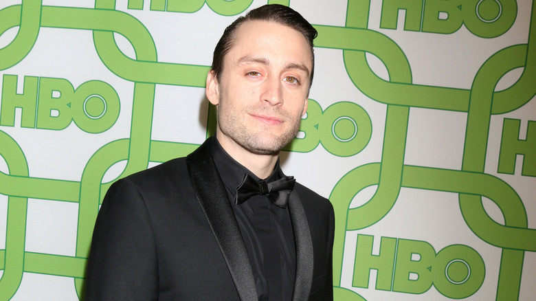 Kieran Culkin wearing a black suit, shirt, and tie on the red carpet at an HBO event