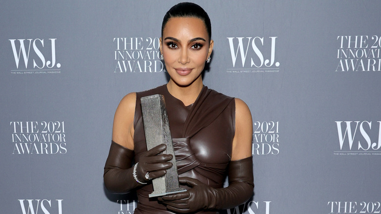 Kim Kardashian holding up award on red carpet