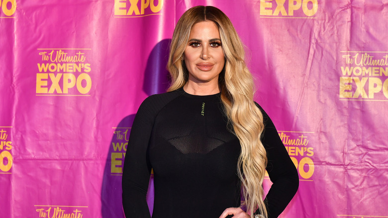 Kim Zolciak smiling in front of pink backdrop