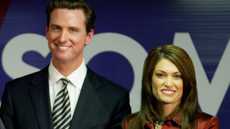 Kimberly Guilfoyle and Gavin Newsom smile on stage