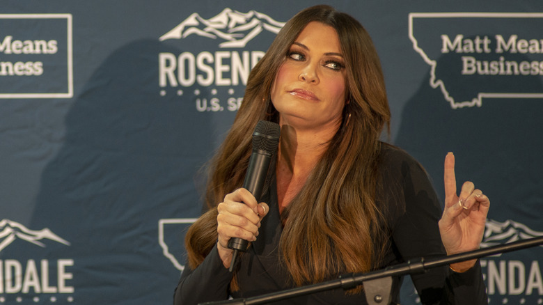 Kimberly Guilfoyle grasping microphone and holding one finger up