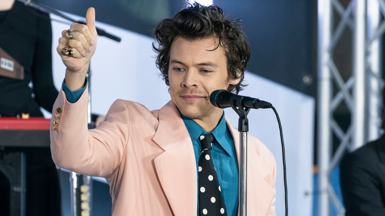 Harry Styles giving a thumbs up on stage