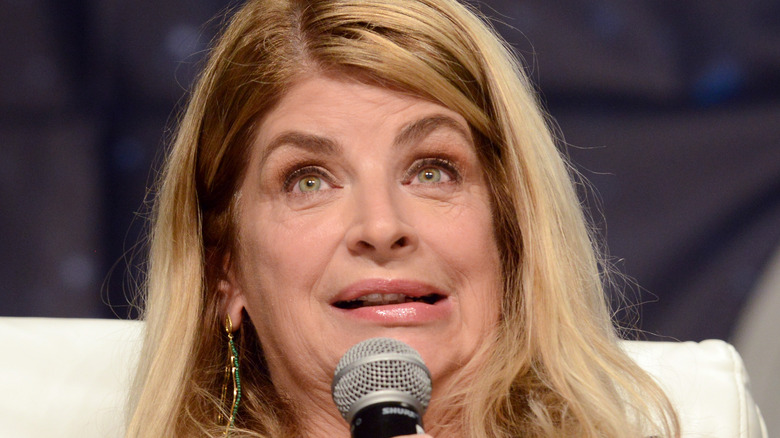 Kristie Alley speaks into a microphone on stage