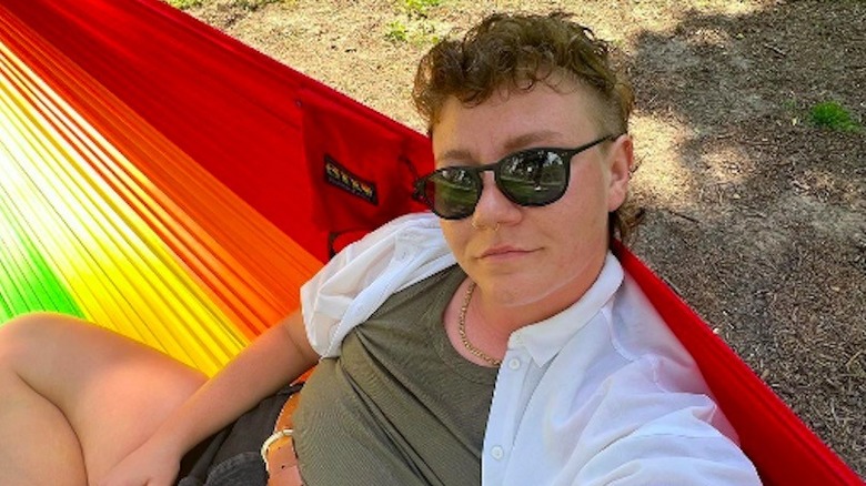 Leon Brown sitting on a rainbow-colored hammock