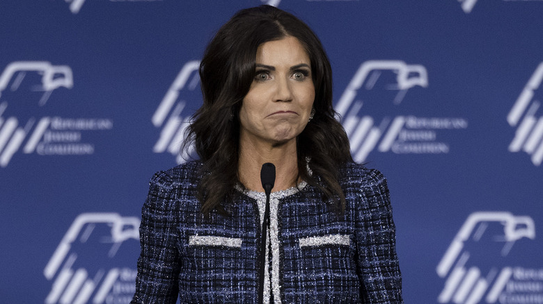 Kristi Noem speaking in front of a microphone