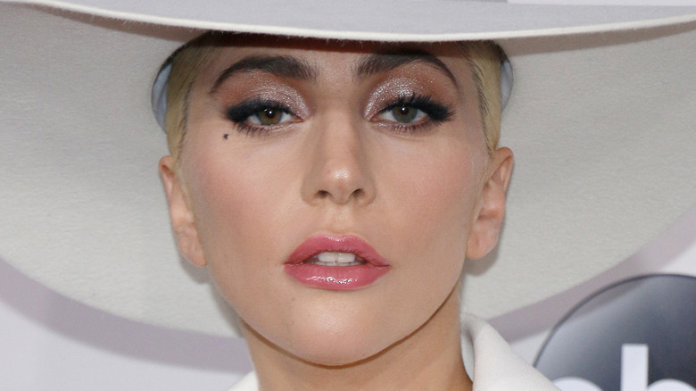 Lady Gaga with hat and serious expression on the red carpet