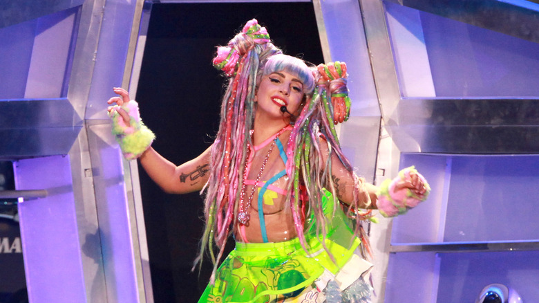 Lady Gaga performing wearing colorful pigtail dreadlocks and a see through neon outfit with furry gloves
