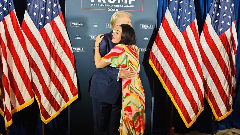 Laura Loomer hugging Donald Trump with flags