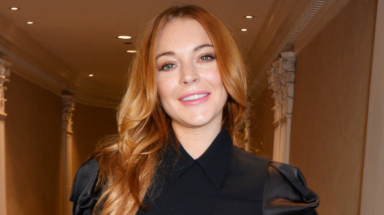 Lindsay Lohan smiling in a fancy hallway