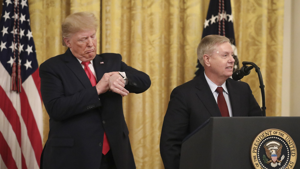 Donald Trump pretends to check his watch after Sen. Lindsey Graham (R-SC) mentioned upcoming Senate votes during an event about judicial confirmations in the East Room of the White House on November 6, 2019 in Washington, DC.