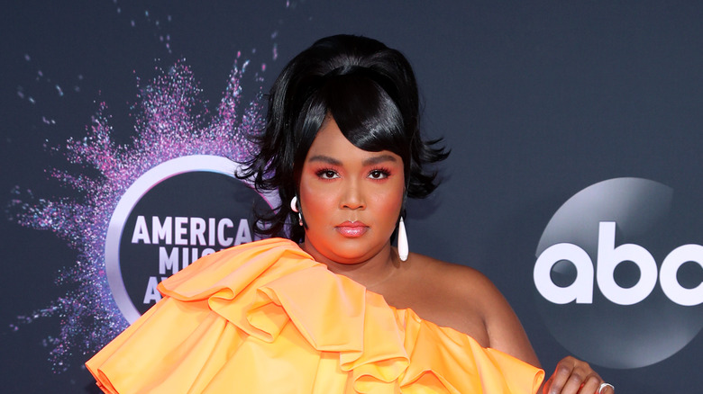 Lizzo in orange dress, posing