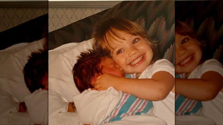 Maddie Ziegler smiling while holding baby Mackenzie