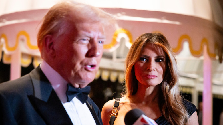 Melania Trump watching Donald Trump speak into microphone at 2024 NYE party