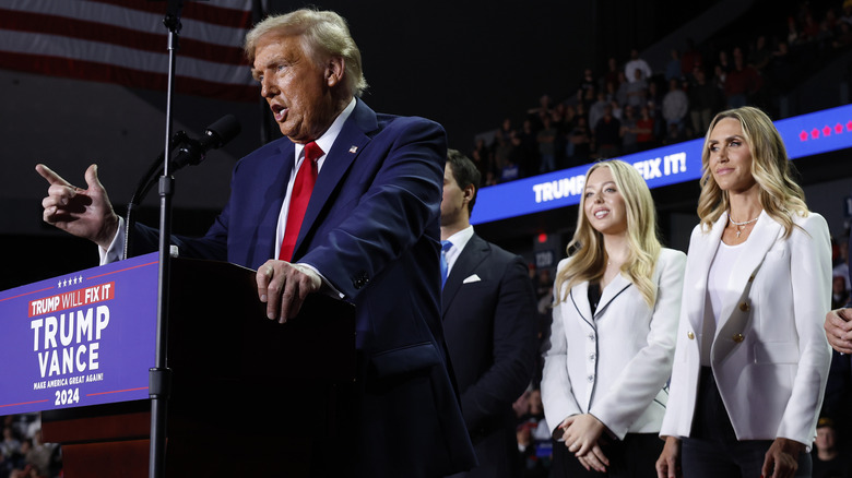 Donald Trump speaking at podium in front of Tiffany and Lara Trump