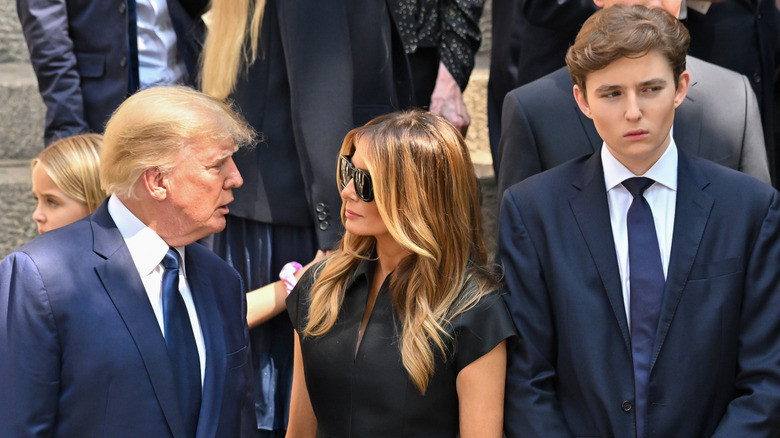 Donald and Melania Trump speaking beside Barron Trump at Ivana Trump's funeral