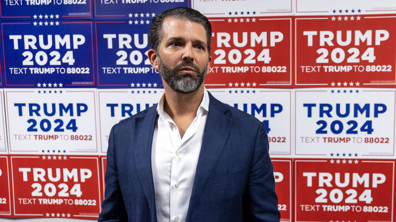 Donald Trump Jr. standing in front of Trump 2024 signs