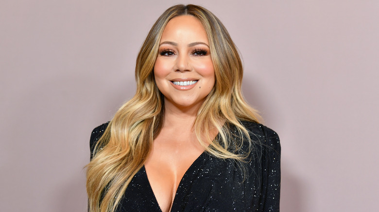 Mariah Carey smiling in a black sparkly outfit