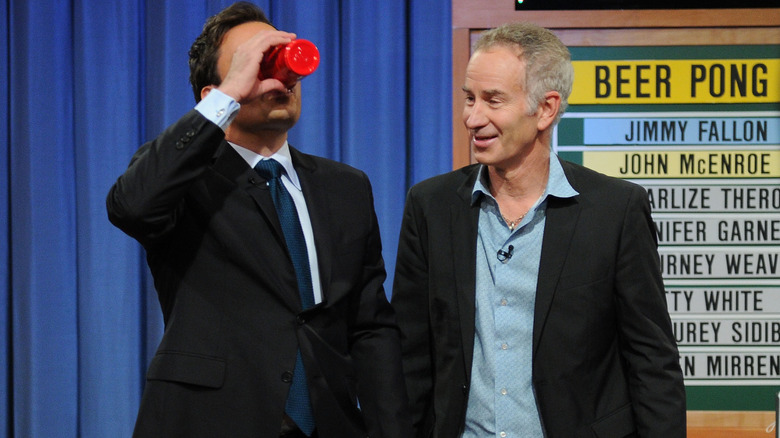 Jimmy Fallon drinking from a red solo cup as John McEnroe looks on