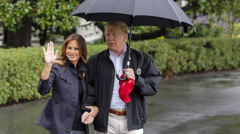 Melania Trump waving, Donald Trump holding umbrella