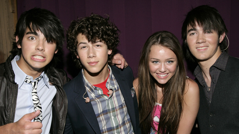 Joe Jonas, Nick Jonas, Miley Cyrus, and Kevin Jonas smiling