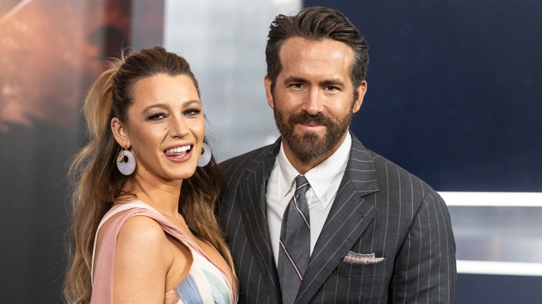 Blake Lively wearing a multi-colored gown with Ryan Reynolds wearing a grey pinstripe suit and tie