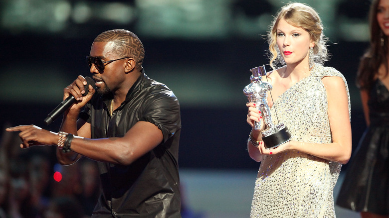 Kanye West yelling into a microphone while Taylor Swift stands