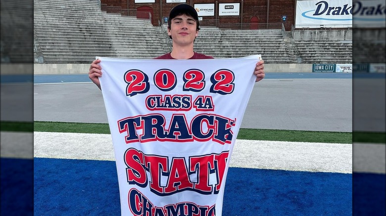 Colin Clark posing with a banner