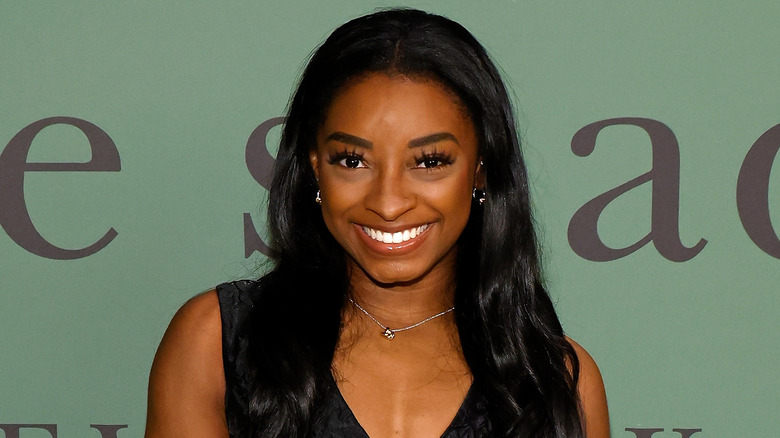 Simone Biles smiling in black dress