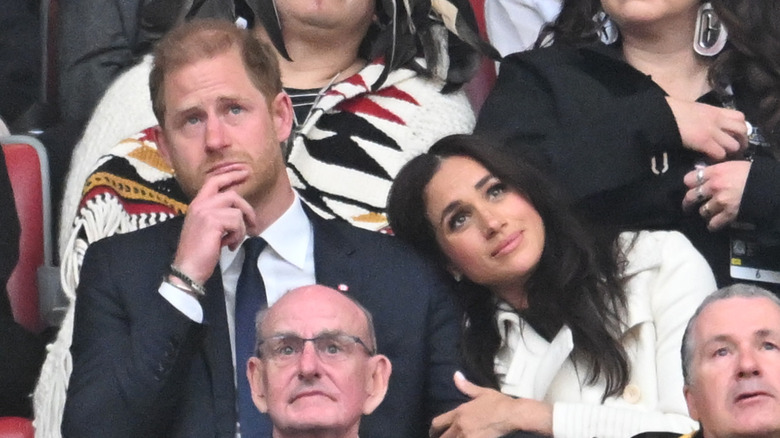 Meghan Markle and Prince Harry cuddling while sitting in crowd