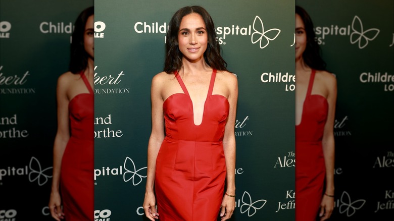 Meghan Markle posing at the CHLA gala in a red dress