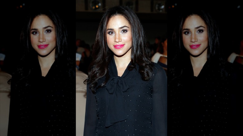 Meghan Markle wearing bright pink lipstick and black clothes