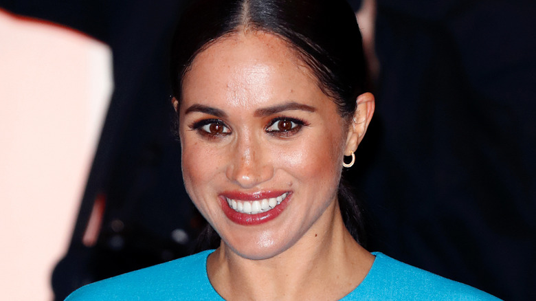 Meghan Markle wearing bold makeup and a blue top