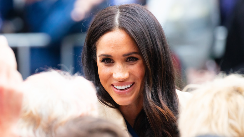 Meghan Markle smiling in a crowd