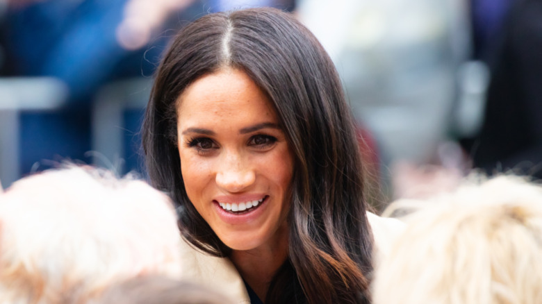 Megan Markle smiling and talking to two children