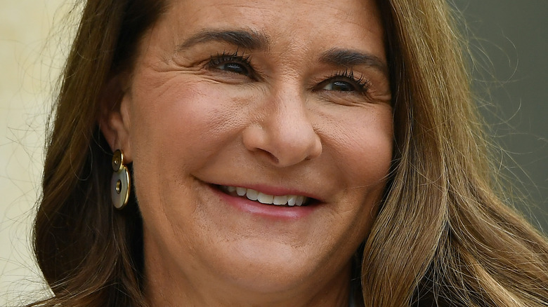 Melinda Gates smiles in gold and blue earrings