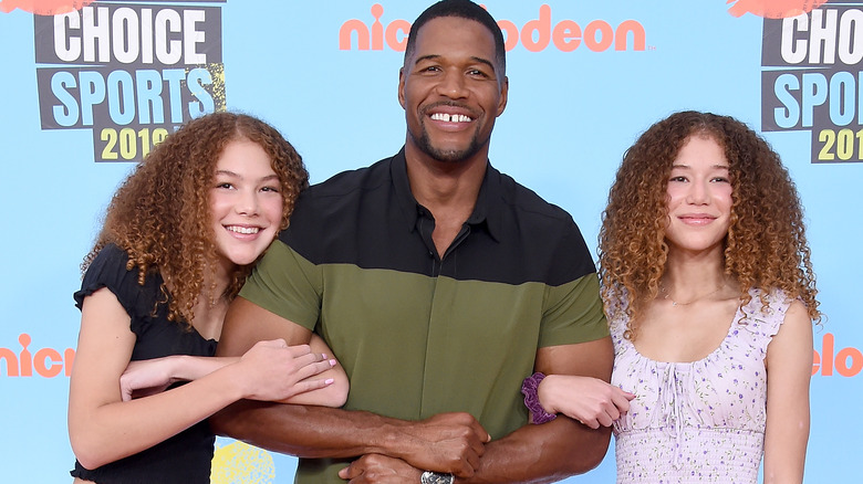 Michael Strahan stands with his twin daughters at red carpet event